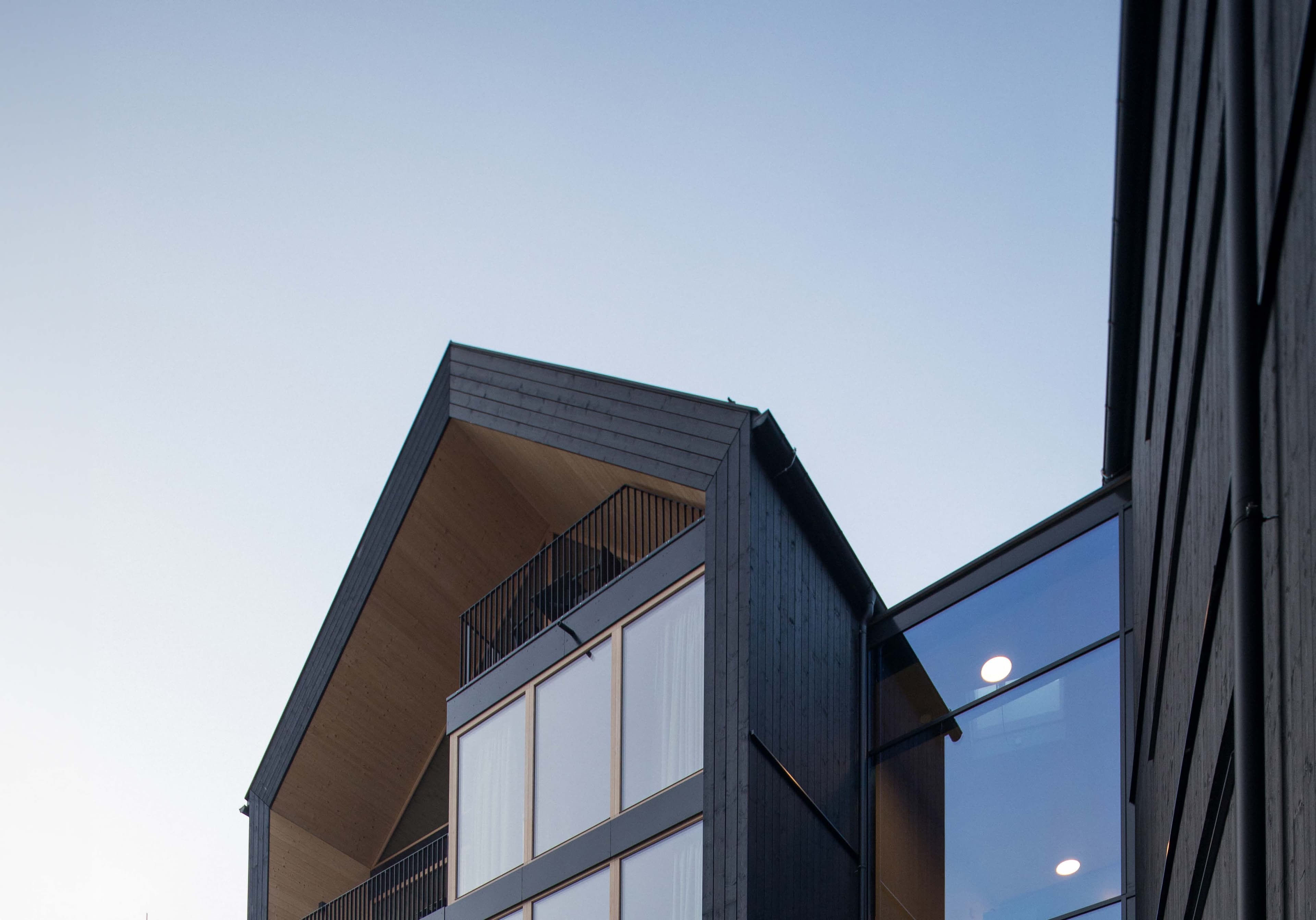 Gable of the SUITES Montafon with black timber facade and glass front against the evening sky