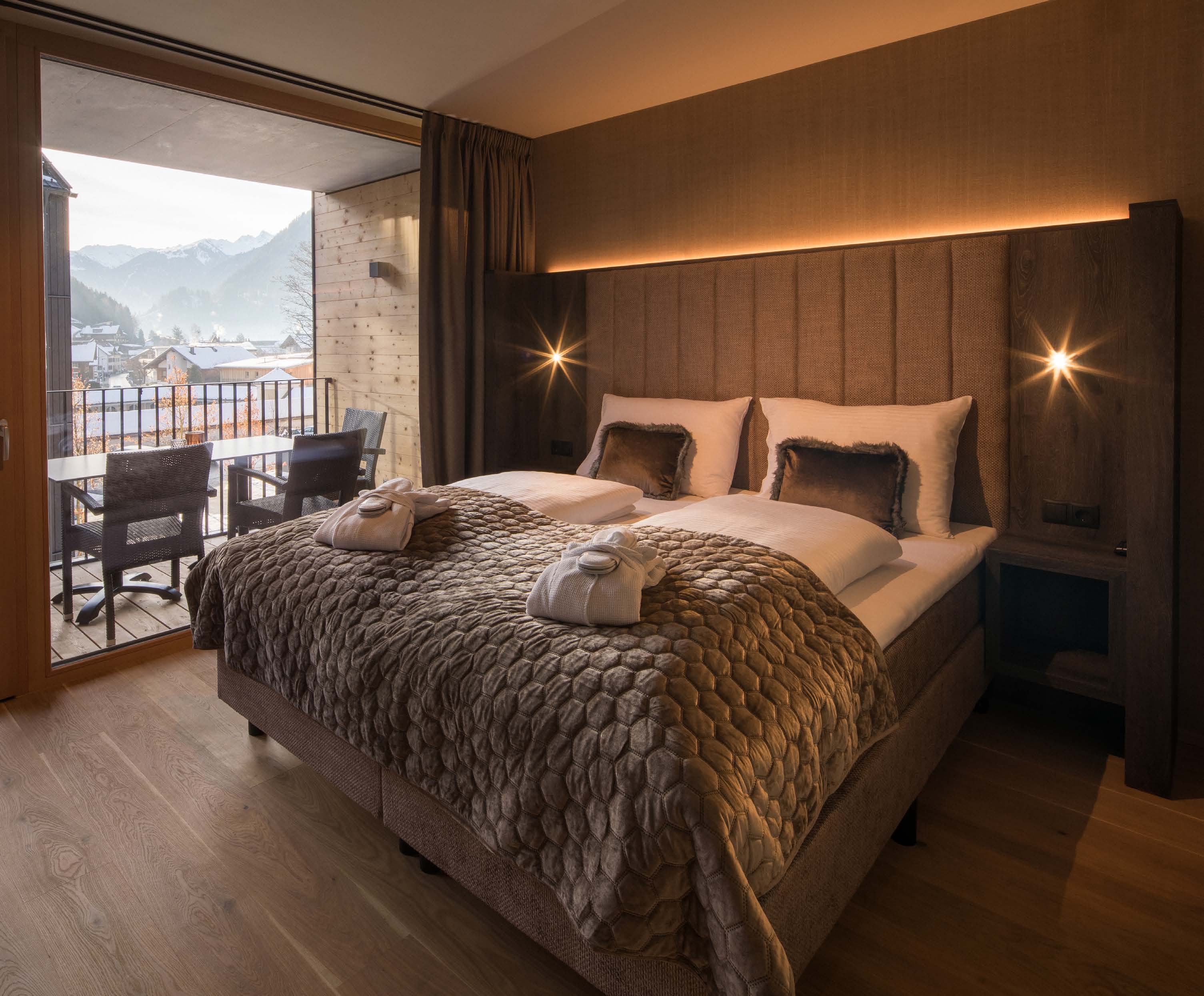 Bedroom with box spring bed and open balcony door with mountain view
