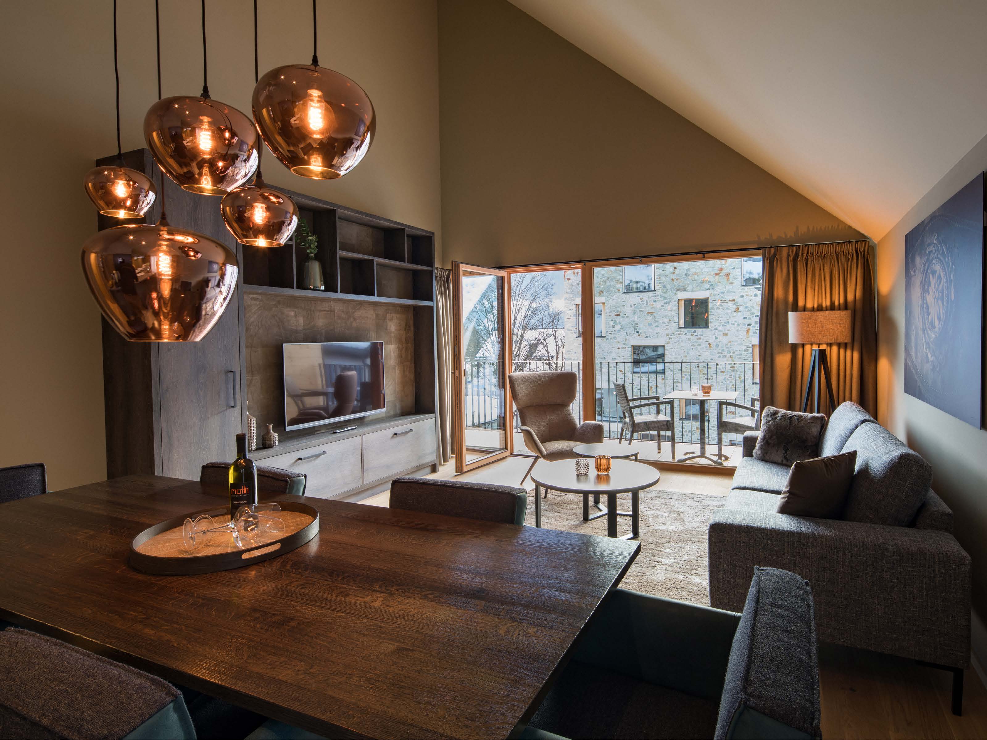 Penthouse living area with copper pendant lights, dining table and sloping ceiling