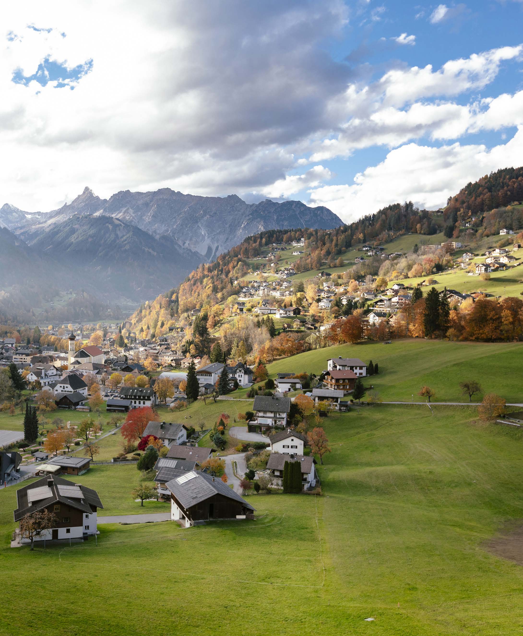 Schruns in autumn from above with church, meadows and mountains